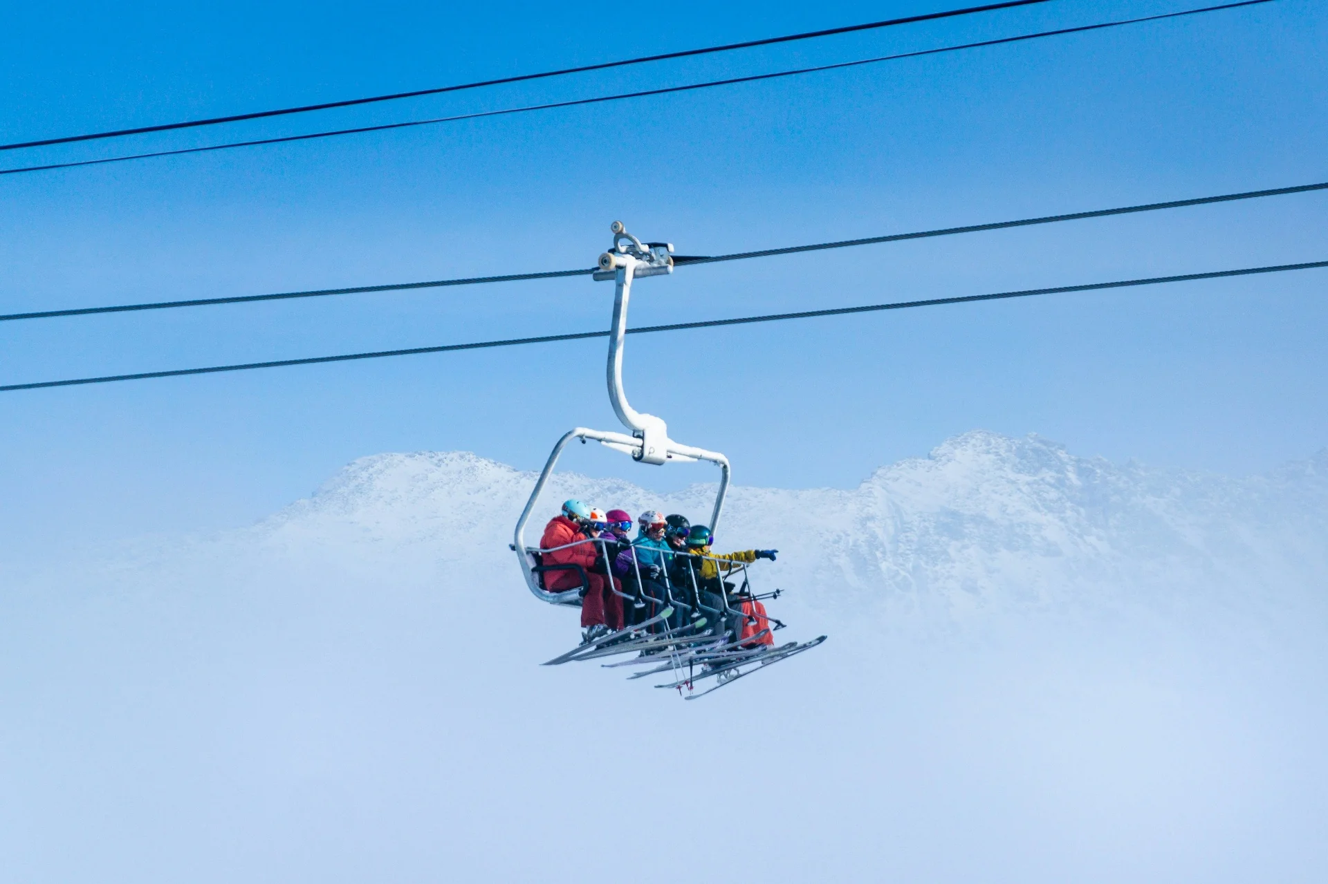 Skifahrer im Sessellift vor verschneitem Bergpanorama